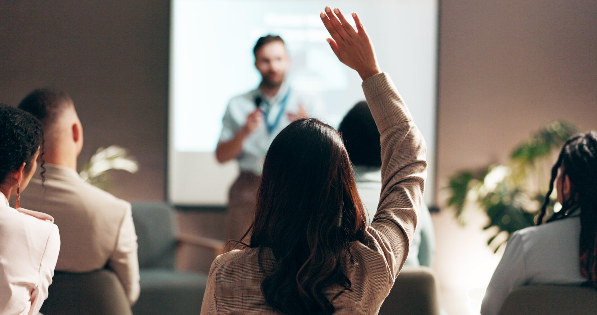 Person raising hand during a presentation.